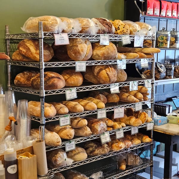 A bakery display rack filled with various types of fresh bread loaves and pastries.
